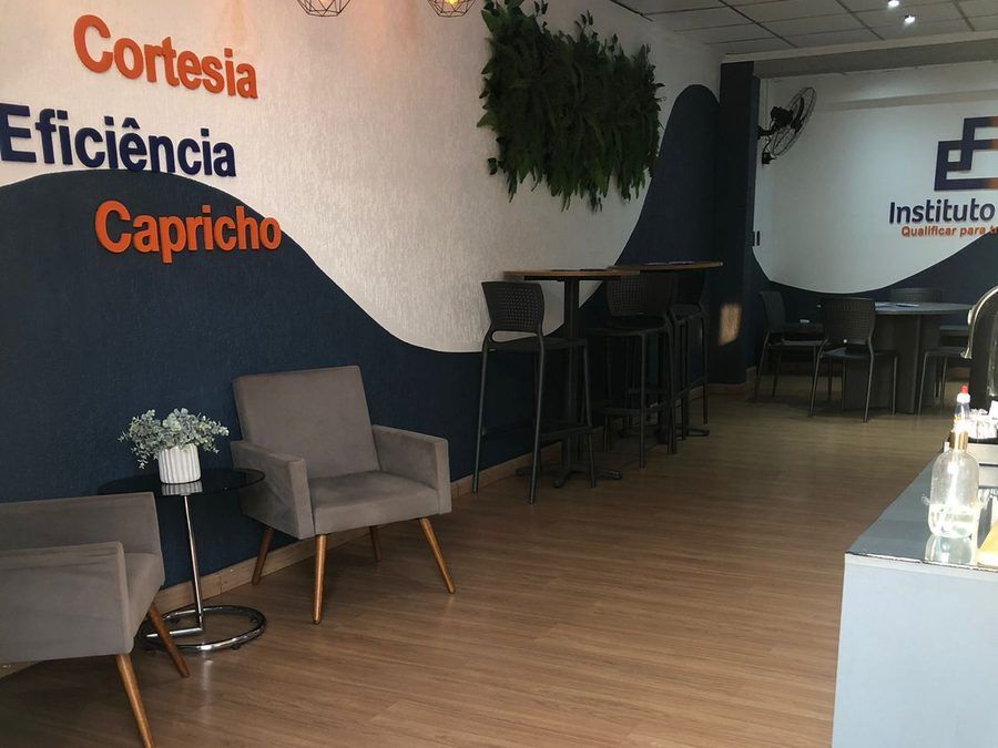 Recepção do polo do Instituto Focar, com poltronas, mesas altas e a parede com os valores Cortesia, Eficiência e Capricho