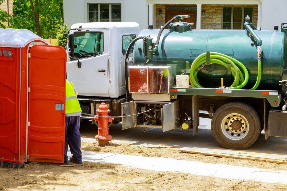 A Man is Standing Next to a Portable Toilet and a Vacuum Truck — KYK Industries in Katherine, NT