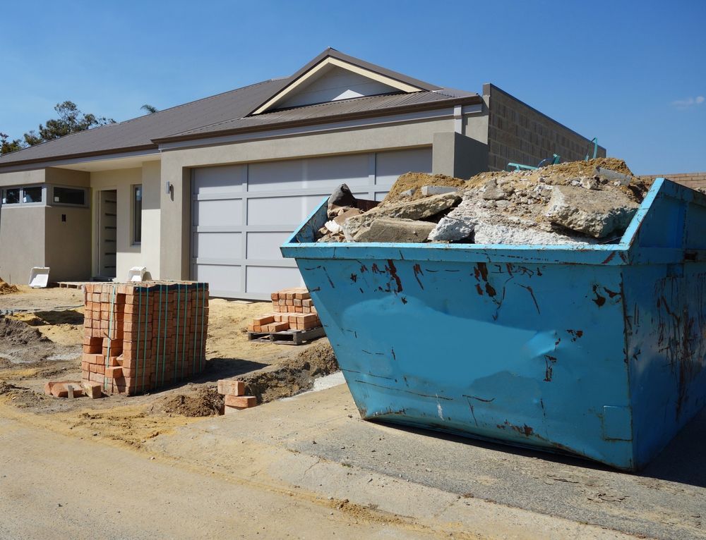 A Blue Dumpster is Sitting in Front of a House — KYK Industries in Katherine, NT
