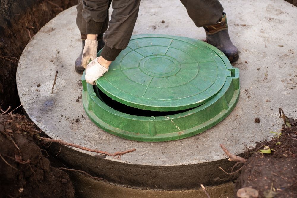 A Man is Opening a Green Manhole Cover on a Septic Tank — KYK Industries in Katherine, NT