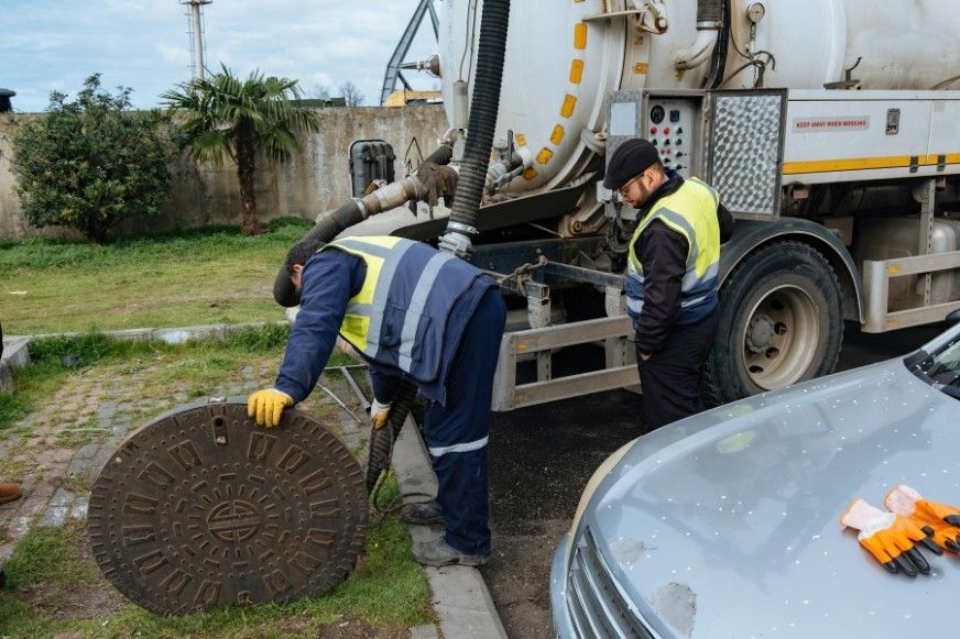 Two Men Are Working on a Manhole Cover Next to a Truck — KYK Industries in Katherine, NT