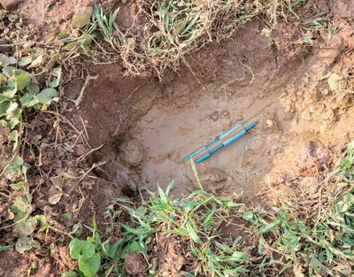 a hole in the ground with a blue pen in it.