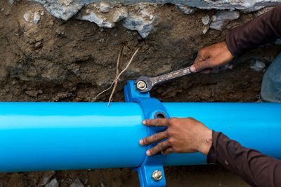 a man is working on a blue pipe with a wrench.