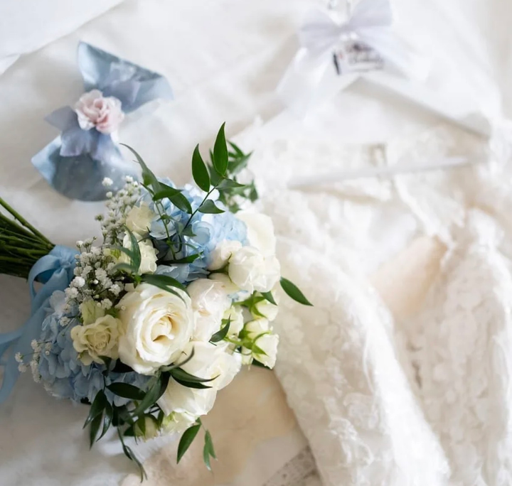 Abito da sposa bianco con bouquet nuziale blu e bianco su tessuto morbido