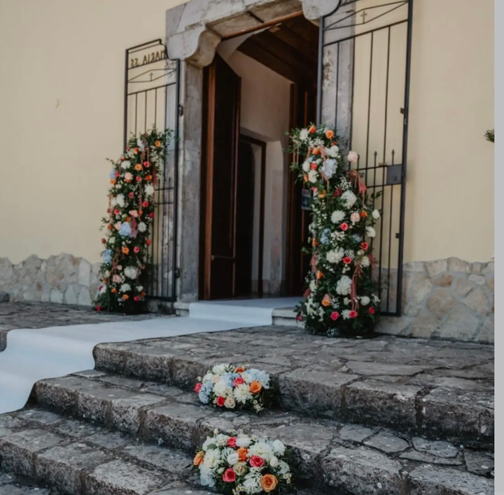 Ingresso decorato con fiori, ghirlande e bouquet sui gradini in pietra.