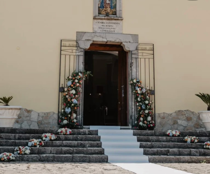 Ingresso della chiesa in pietra con decorazioni floreali e scalini che conducono a una porta buia
