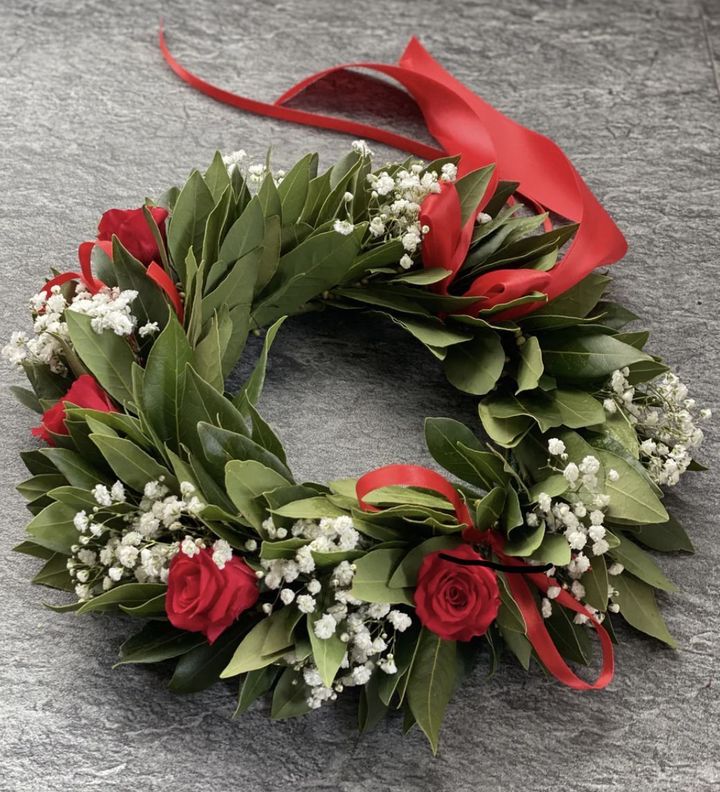 Ghirlanda di fiori rossi con bacche bianche e nastro su una superficie grigia