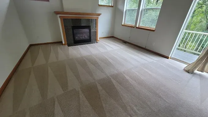 Beige carpeted room with fireplace, windows, and balcony.