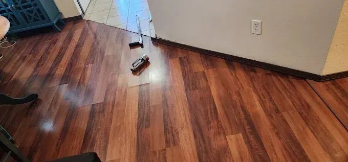 Wooden floor with small objects and a wall with an outlet.