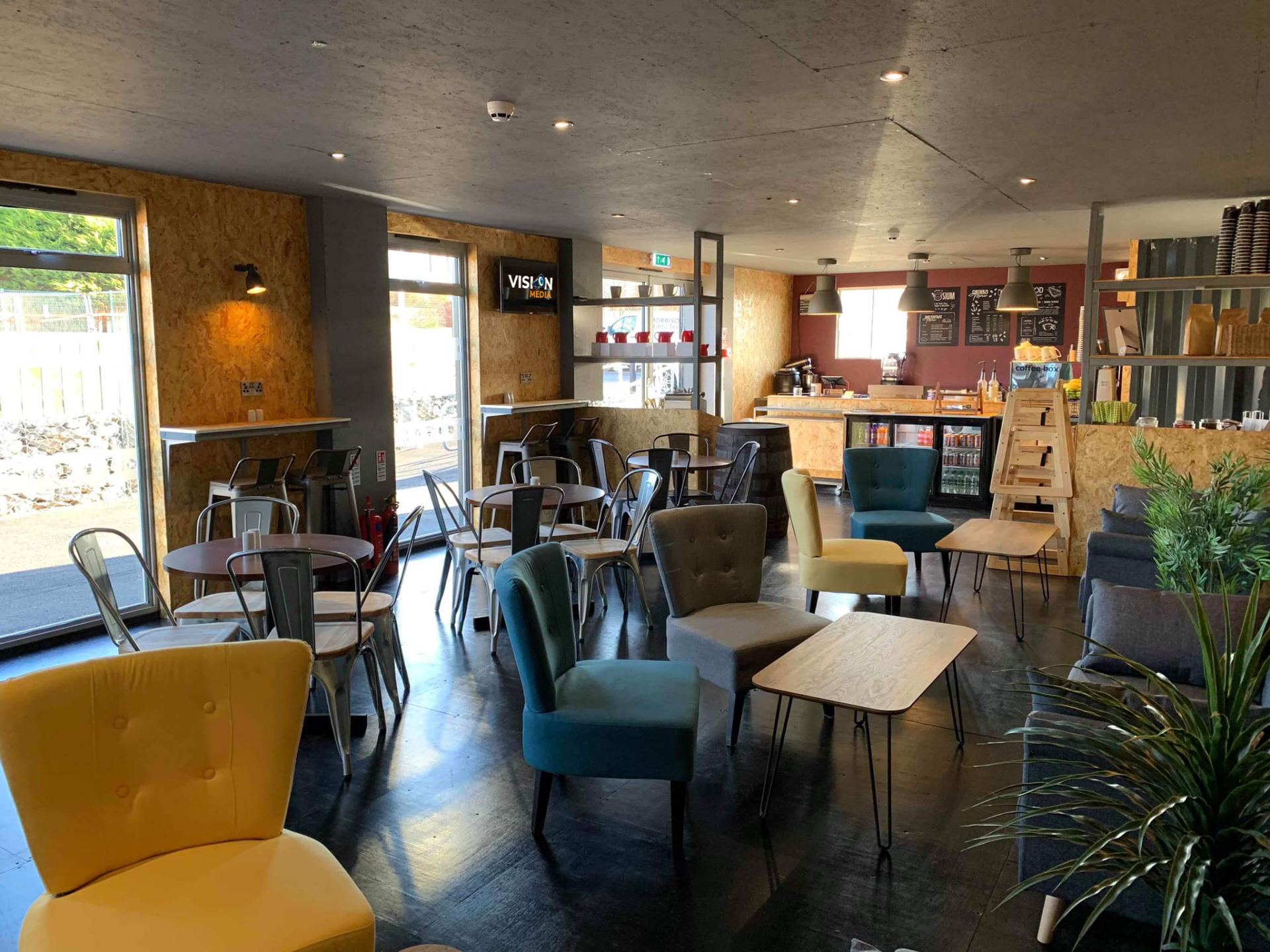 Modern café interior with colorful chairs, tables, bar counter, and large windows