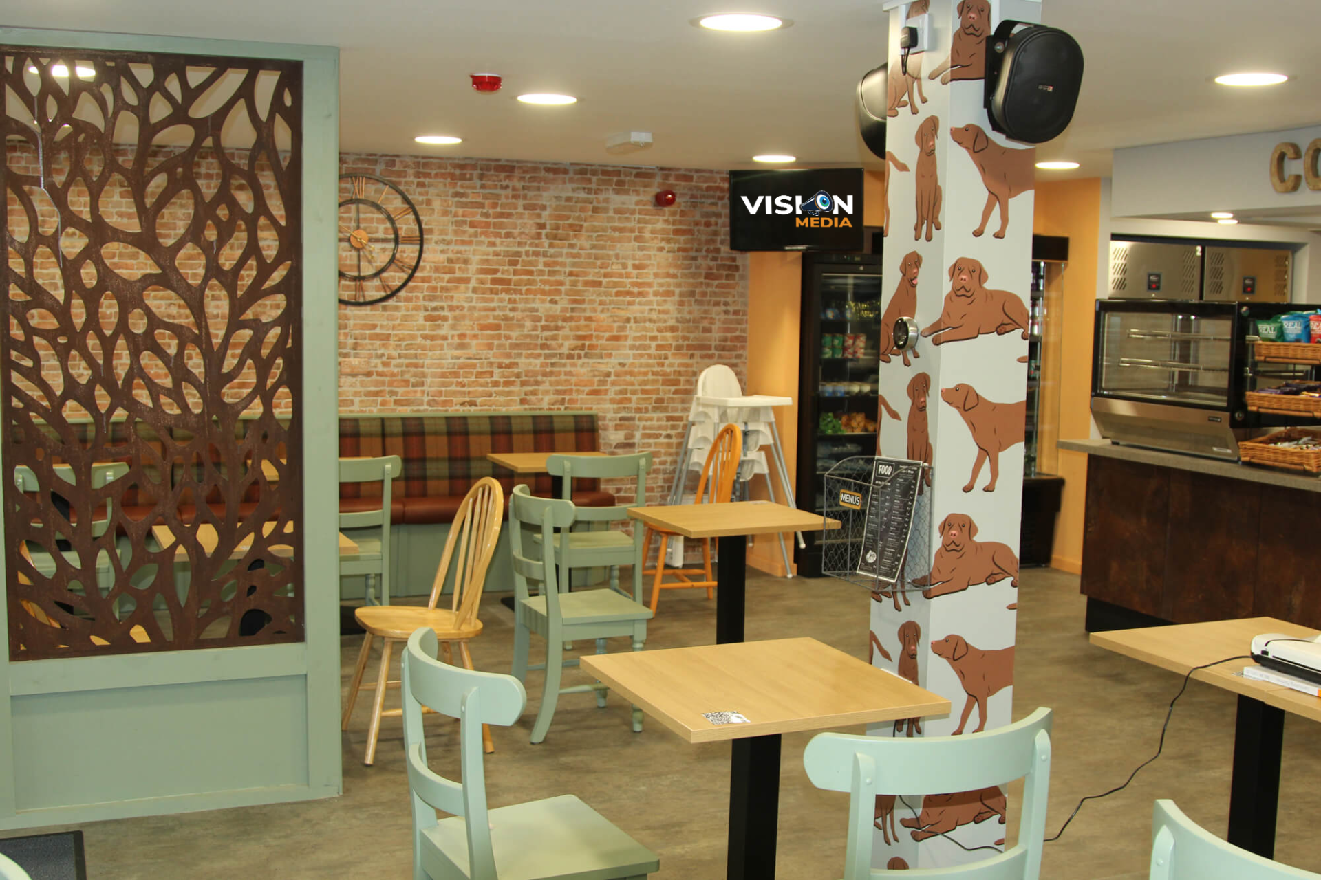 Bright café interior with tables, white chairs, brick wall, and decorative partition panels