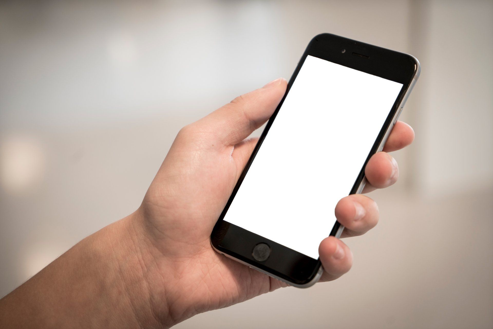 Hand holding a black smartphone with a blank white screen.