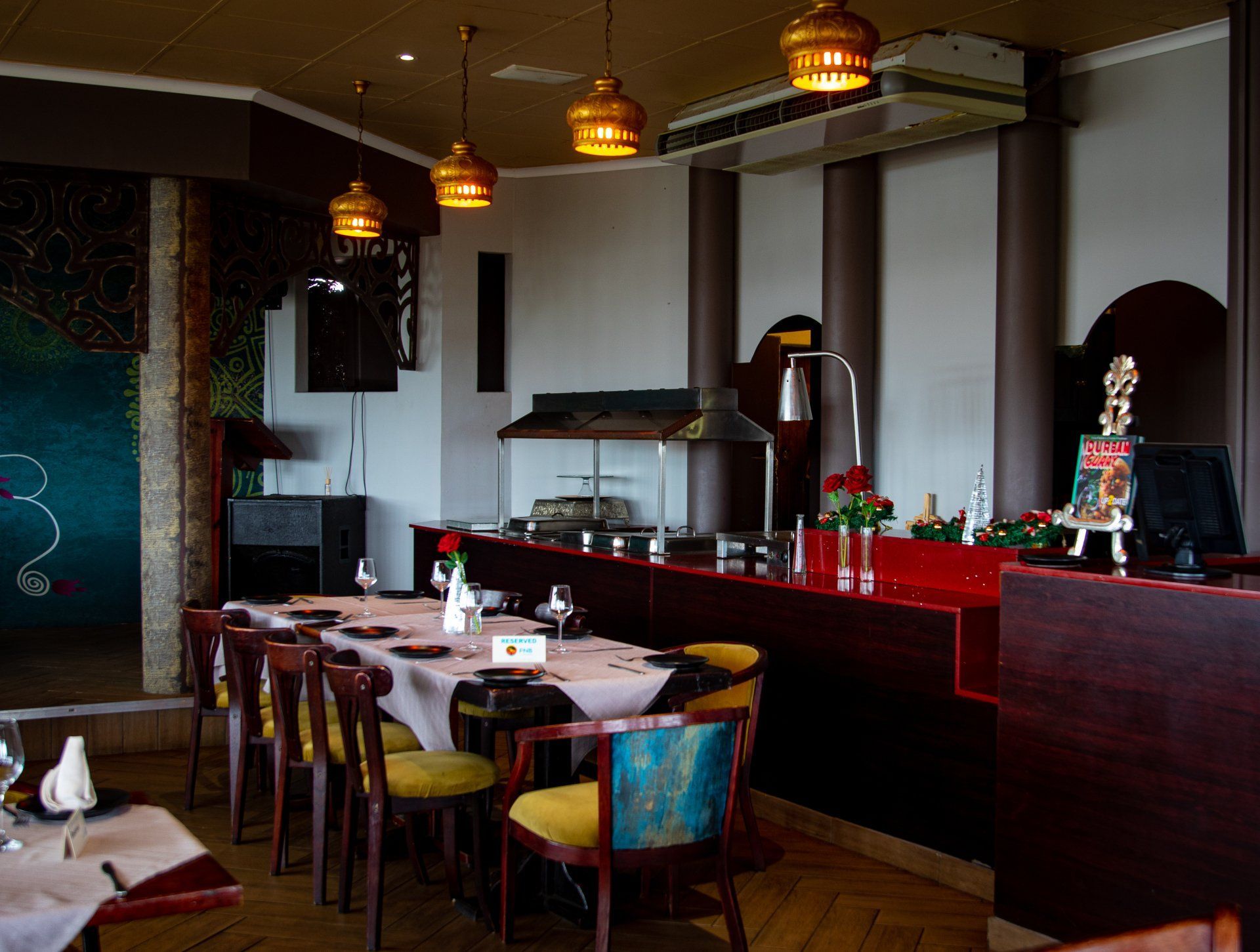 Restaurant interior with tables set for dining, buffet area, warm lighting.