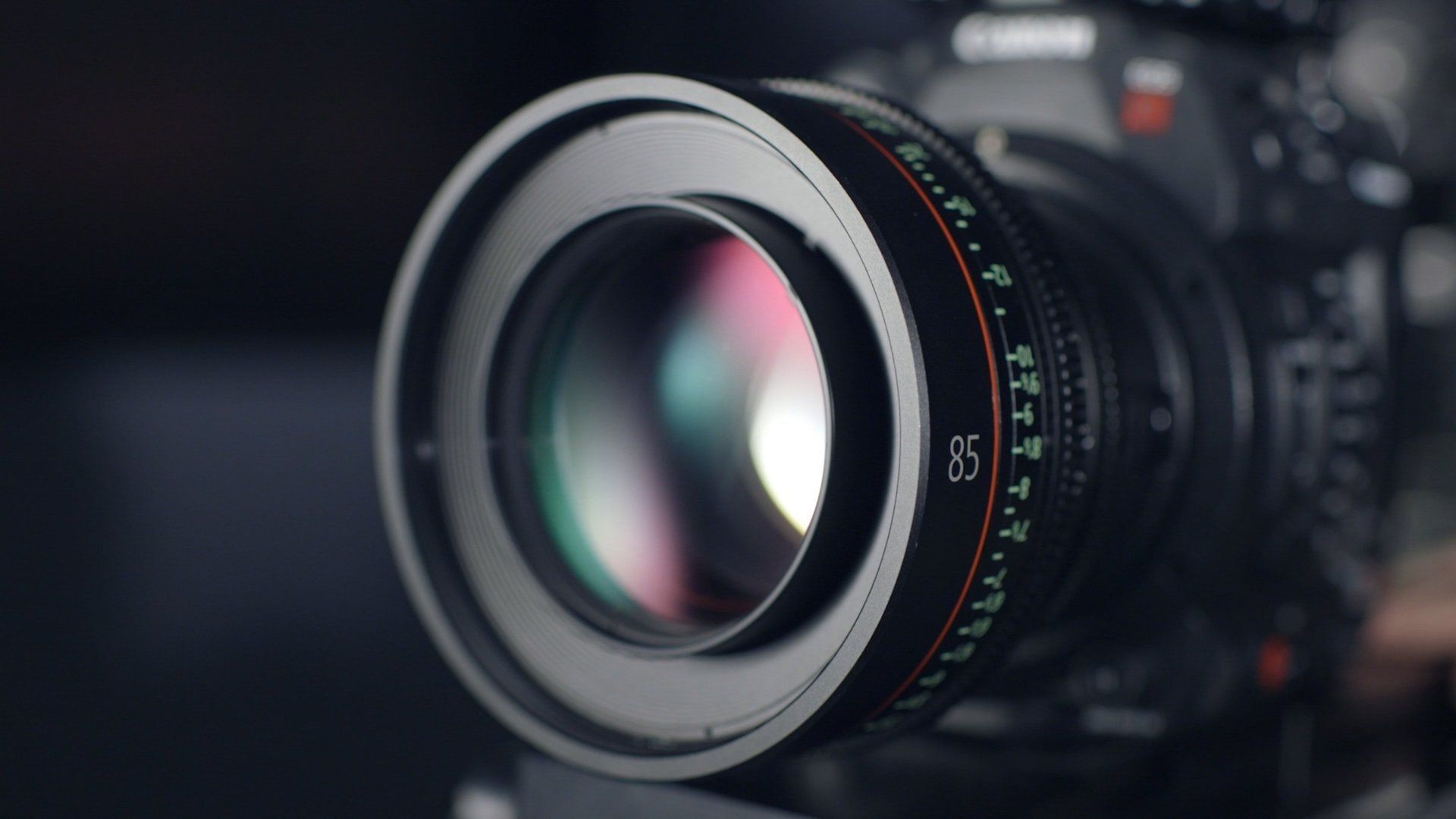 Close-up of a professional camera lens, reflecting colorful light.