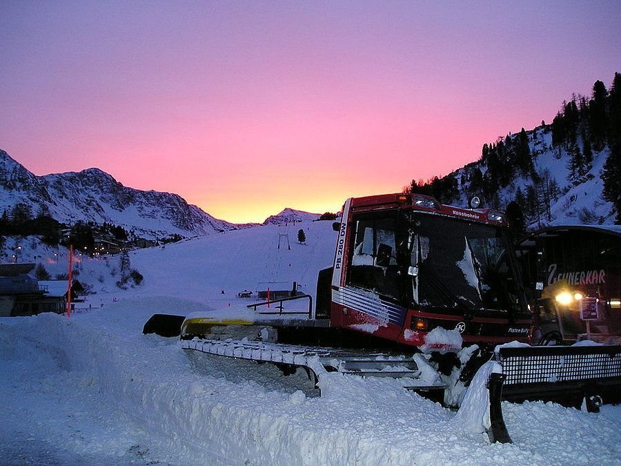 Pistenräumen bei  winterlichem Sonnenuntergang