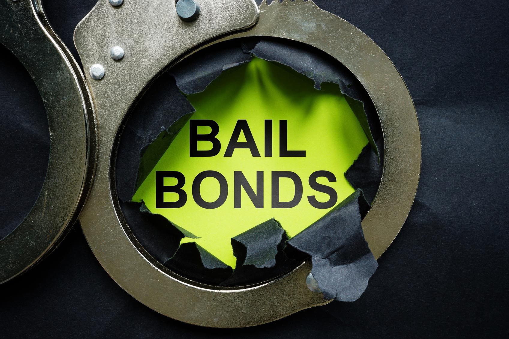 Handcuffs around torn paper showing bold text “BAIL BONDS”.