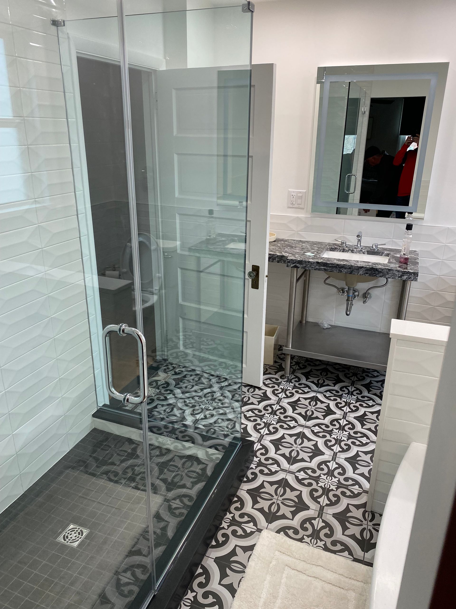 A bathroom with a walk in shower , sink and mirror.