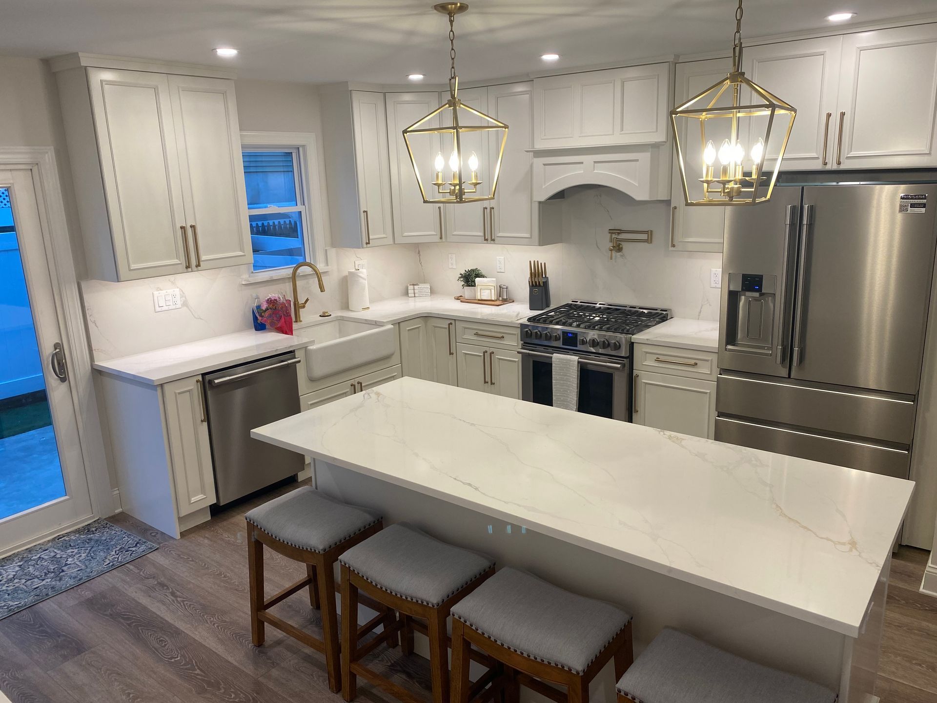 A kitchen with white cabinets , stainless steel appliances , and a large island.