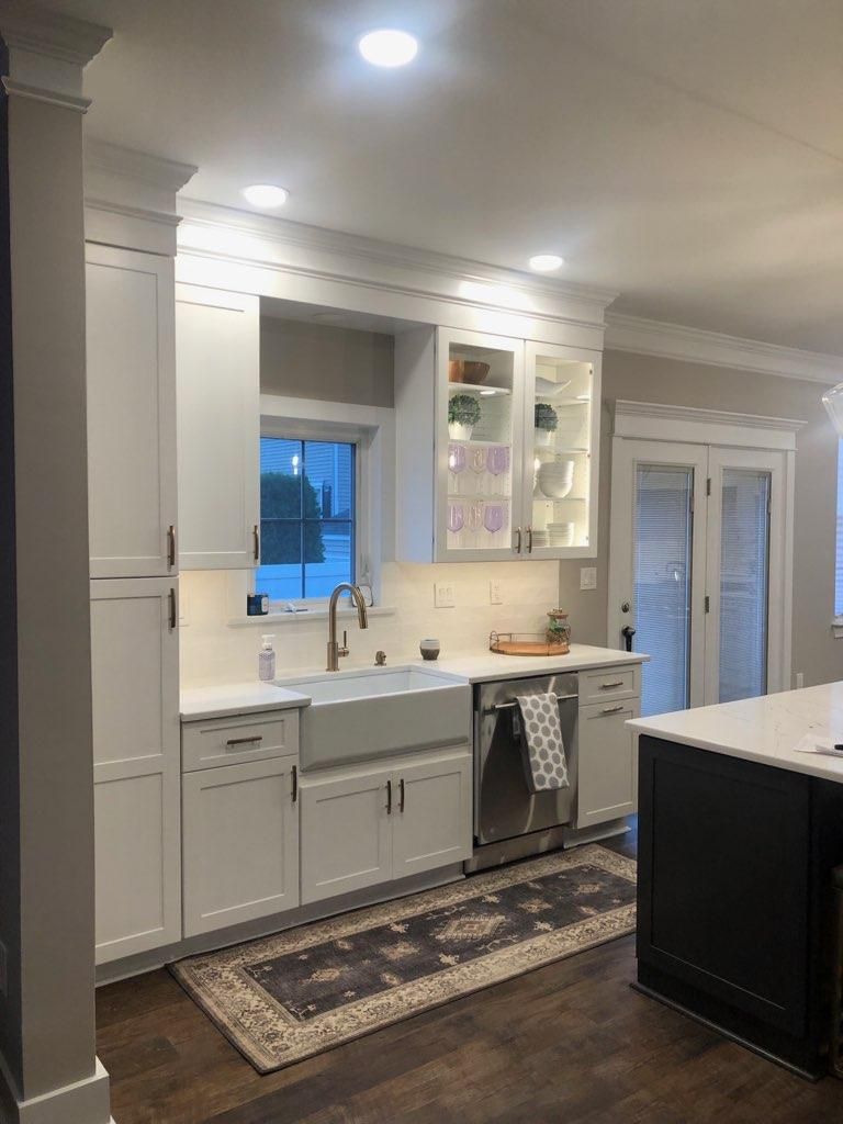A kitchen with white cabinets , stainless steel appliances , a sink , and a rug.