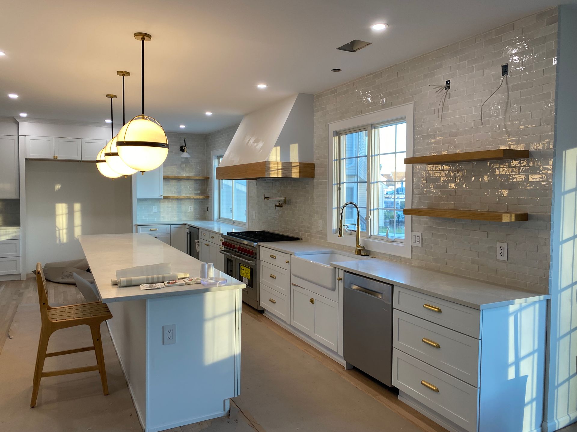 A kitchen with white cabinets , stainless steel appliances , and a large island.