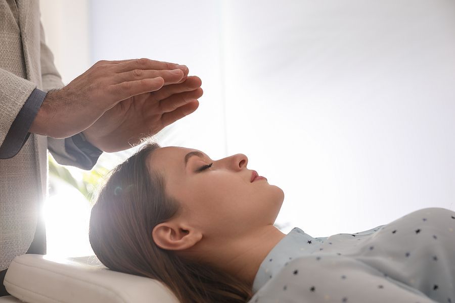 Person receiving energy healing with hands hovering above them.