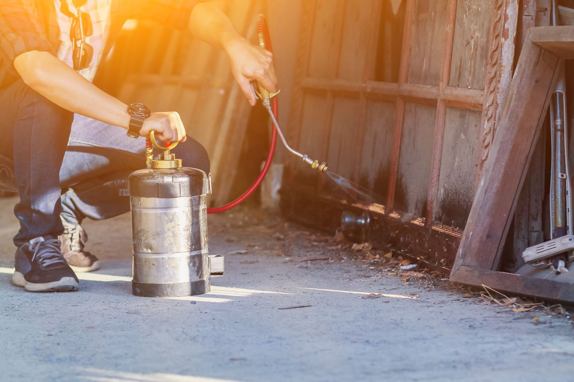 A man in a blue uniform is holding a sprayer and giving a thumbs up
