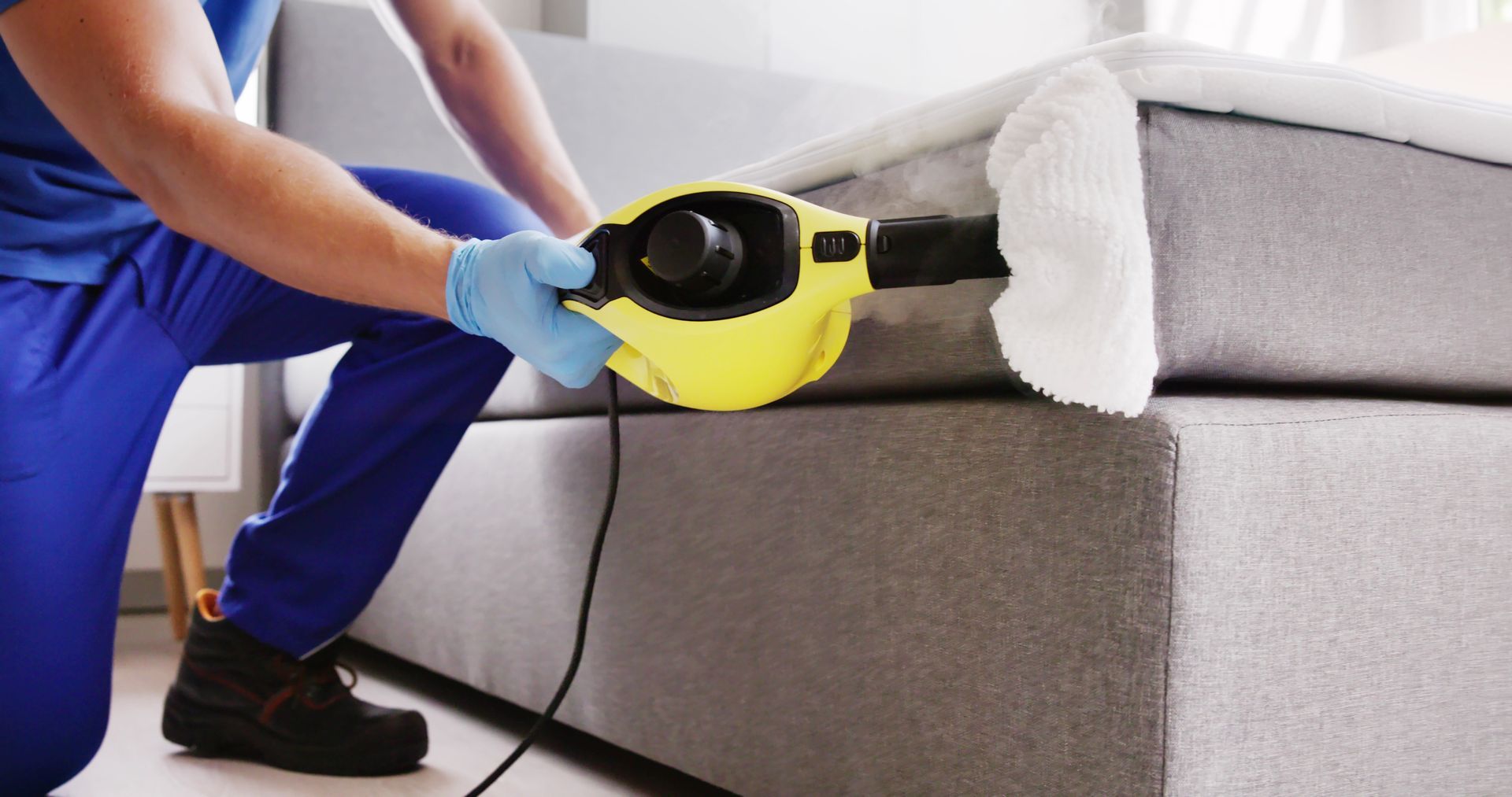 A man in a blue uniform is holding a sprayer and giving a thumbs up