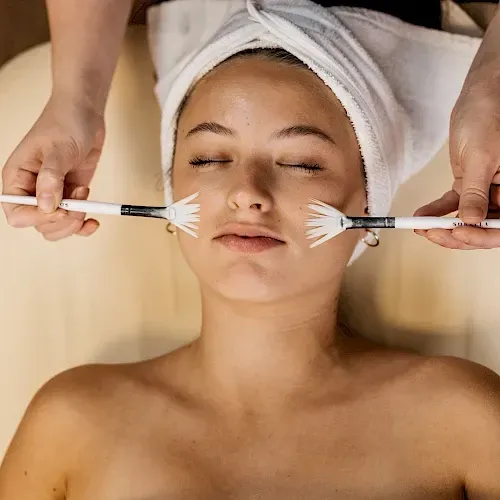 A woman with a towel wrapped around her head is getting a facial treatment.