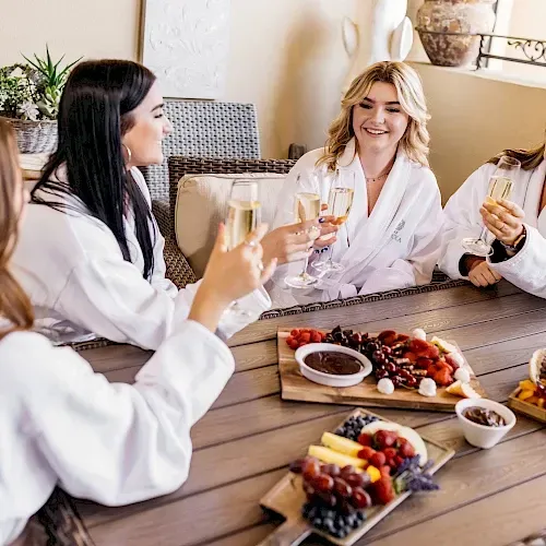 A group of women are sitting at a table toasting with champagne.