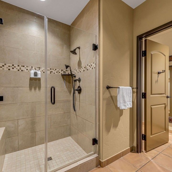 A bathroom with a walk in shower with a glass door