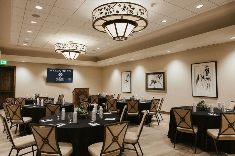 A large room with tables and chairs and a welcome sign on the wall