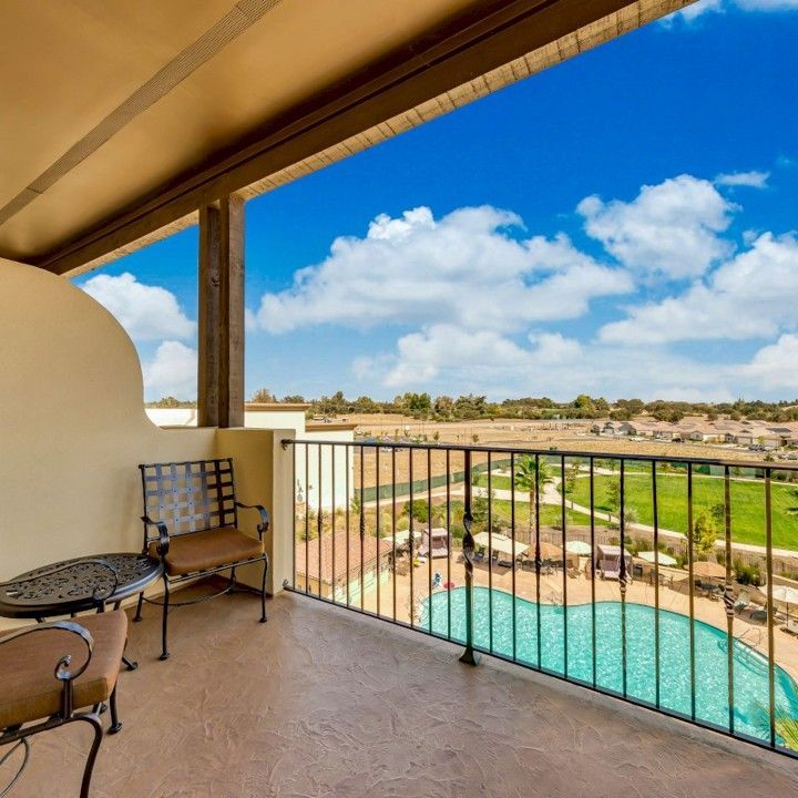 A balcony with a table and chairs overlooking a swimming pool