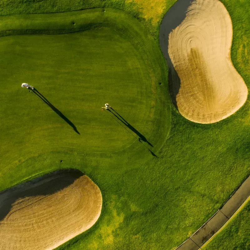 An aerial view of a golf course with a green and sand bunkers.
