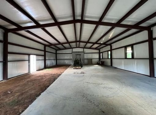 Empty industrial warehouse interior with steel beams, concrete floor, and open side walls