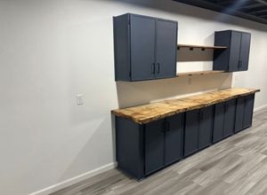 Empty garage wall with navy cabinets and a wood workbench countertop.