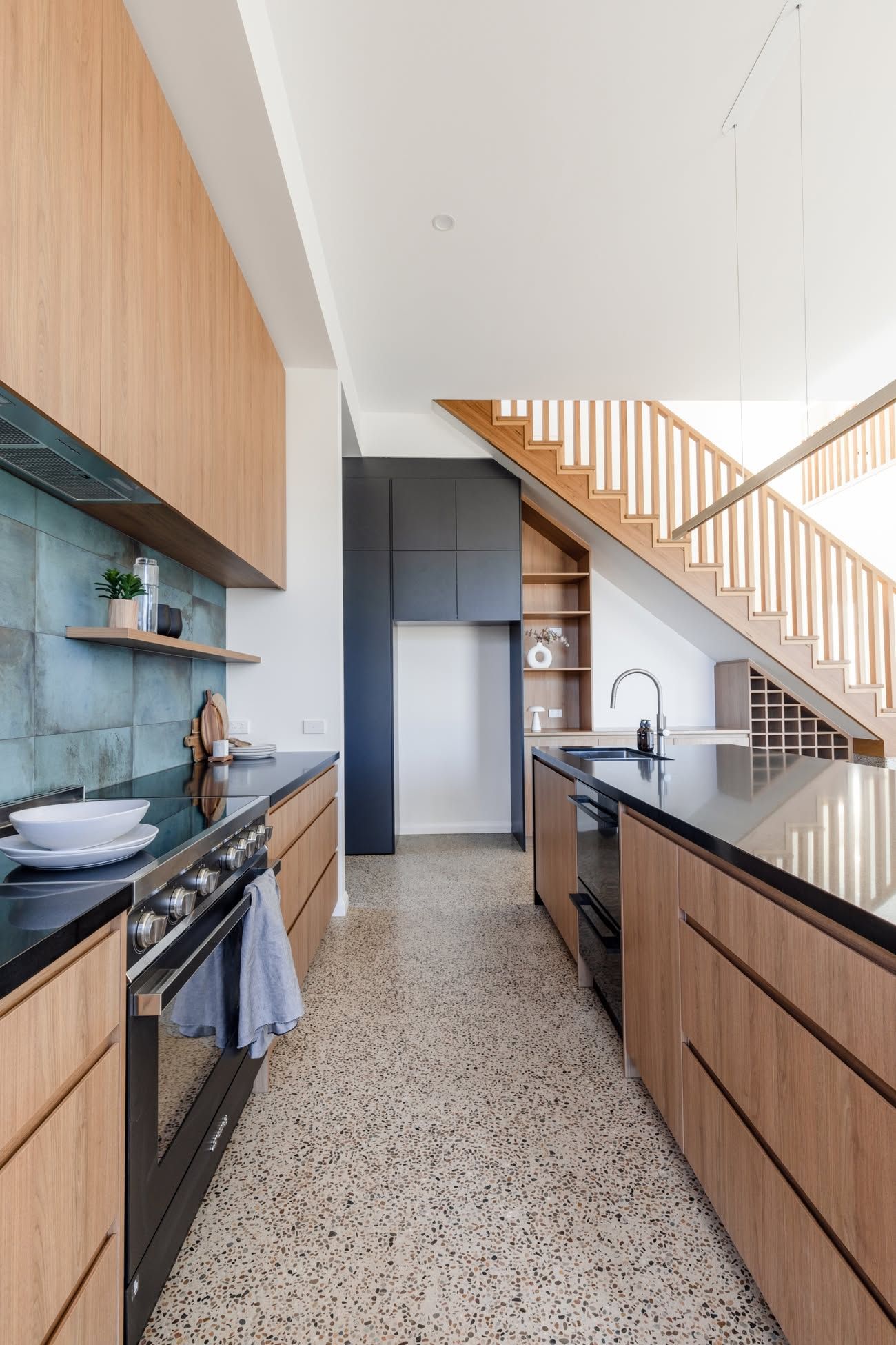 Modern Kitchen with Wood Cabinets, Black Countertops, and A Staircase in The Background — Complete Property Projects In Phillip, ACT