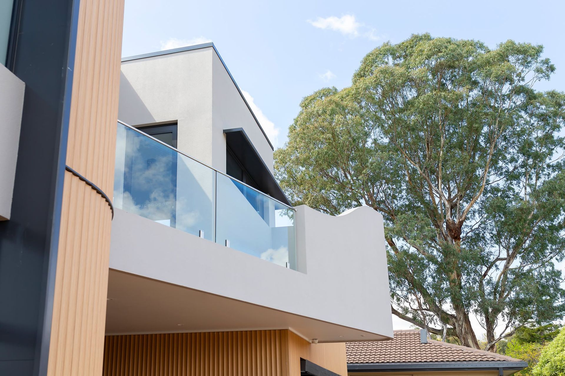 Modern white house with glass balcony and tall tree outside — Complete Property Projects In Phillip, ACT