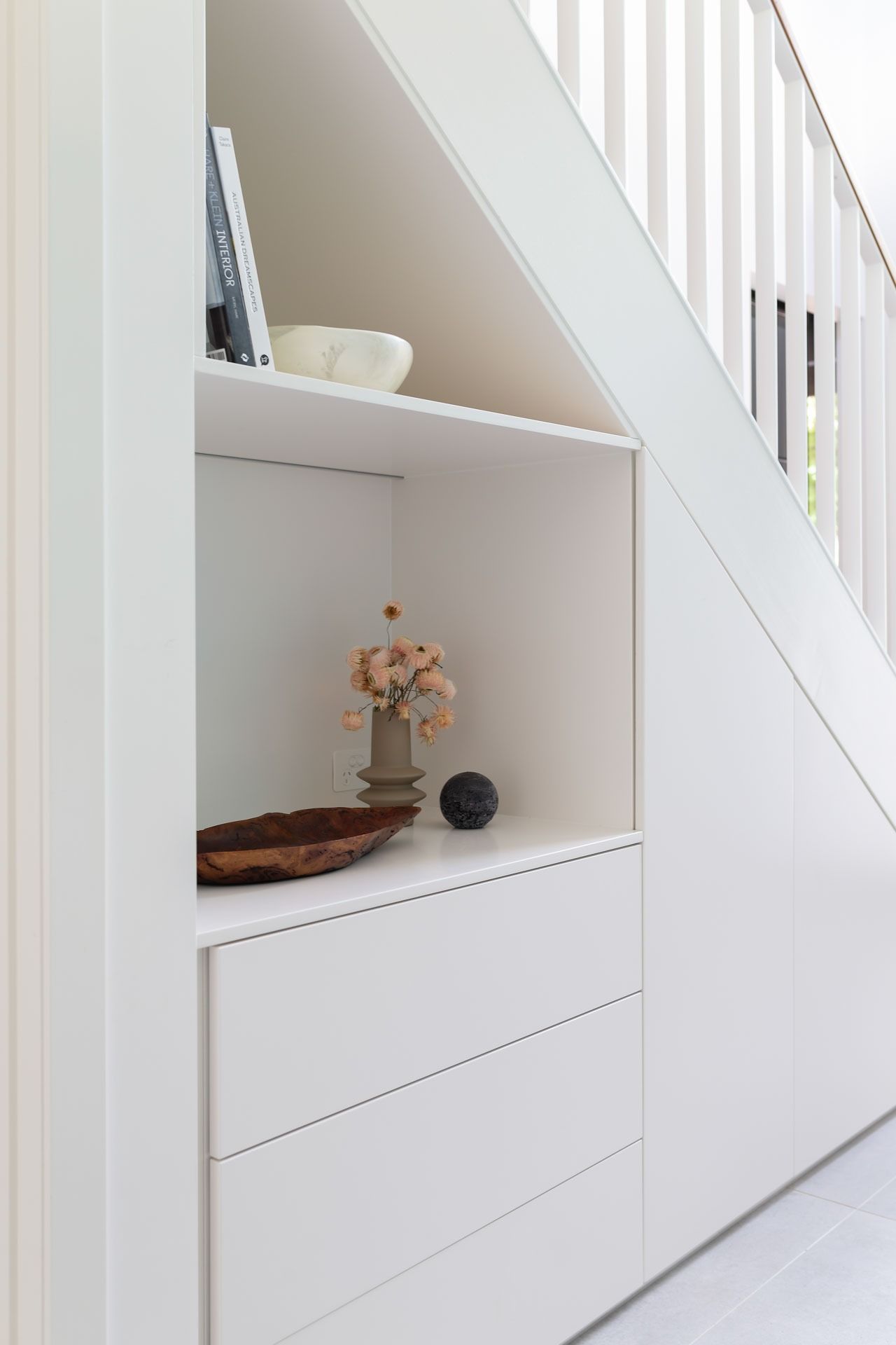 White built-in shelving under a staircase with small decorative items and white drawers — Complete Property Projects In Phillip, ACT