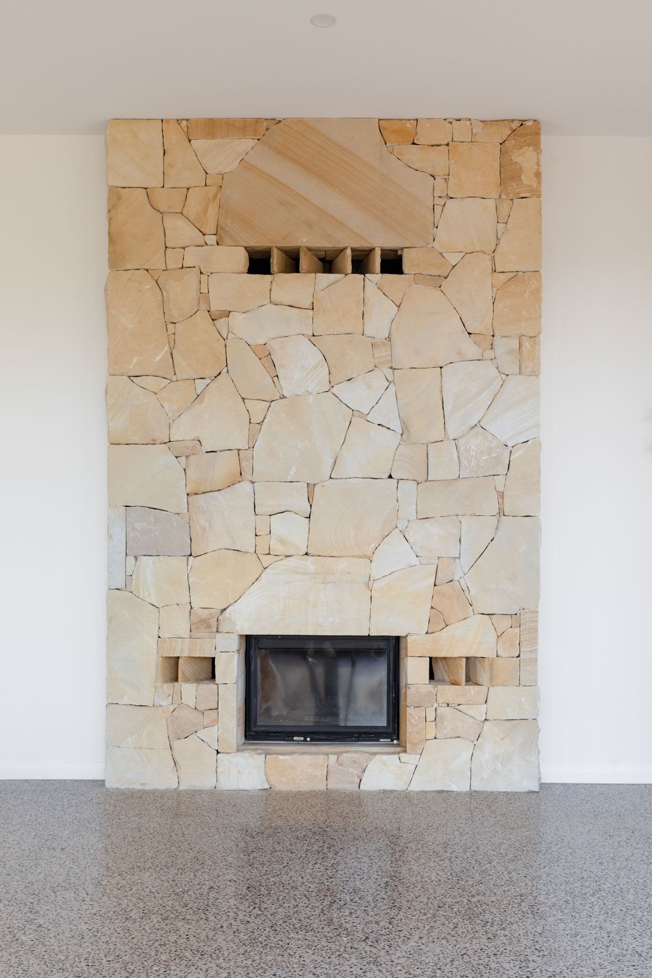 Stone Fireplace Centered on A White Wall with A Black Firebox — Complete Property Projects In Phillip, ACT
