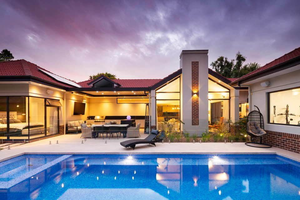 Luxury House with Lit Pool at Dusk and Patio Seating — Complete Property Projects In Phillip, ACT