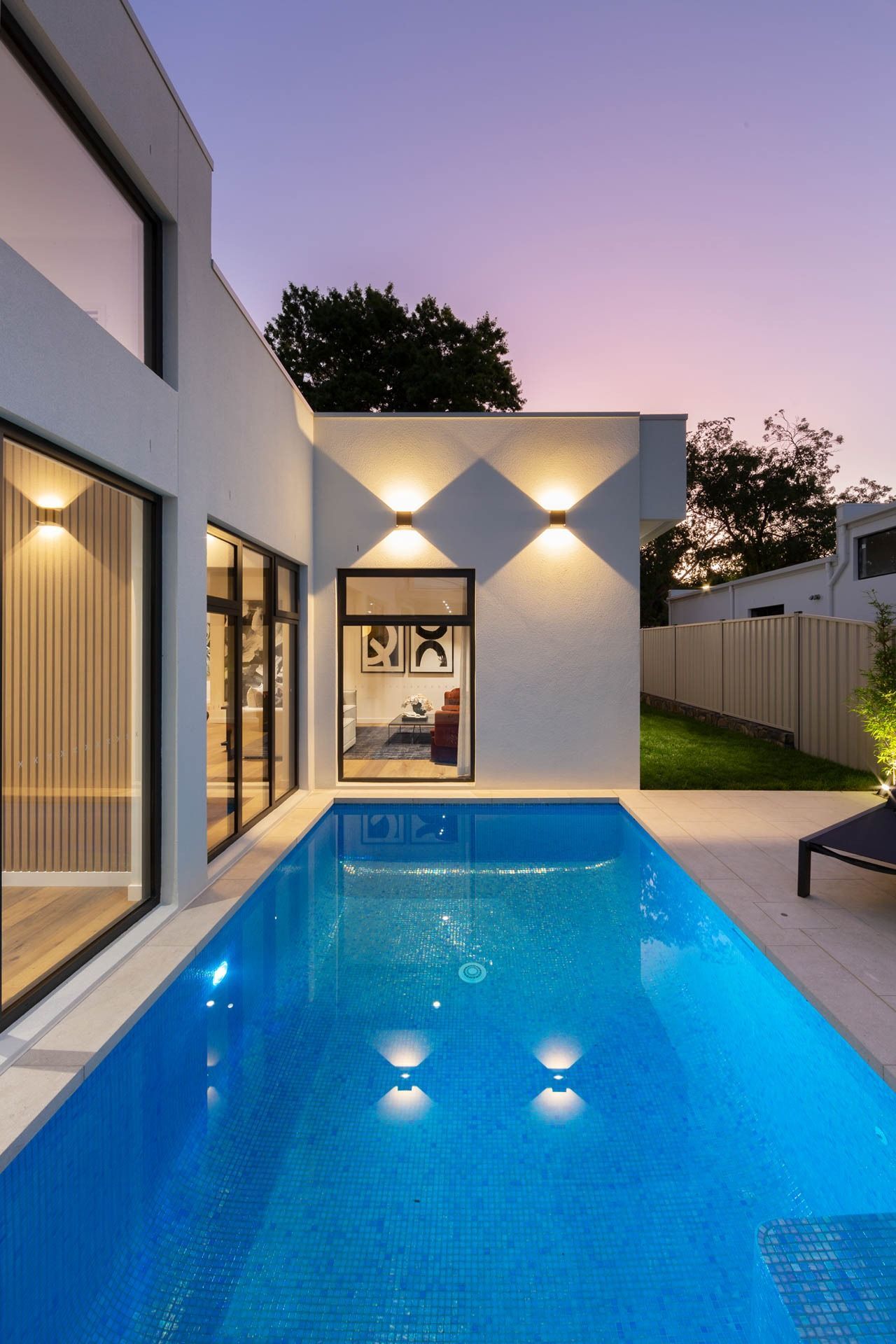 Modern White House with A Lit Backyard Pool at Dusk — Complete Property Projects In Phillip, ACT