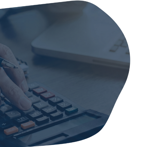 A person’s hands using a white calculator over a document with charts and a yellow sticky note.