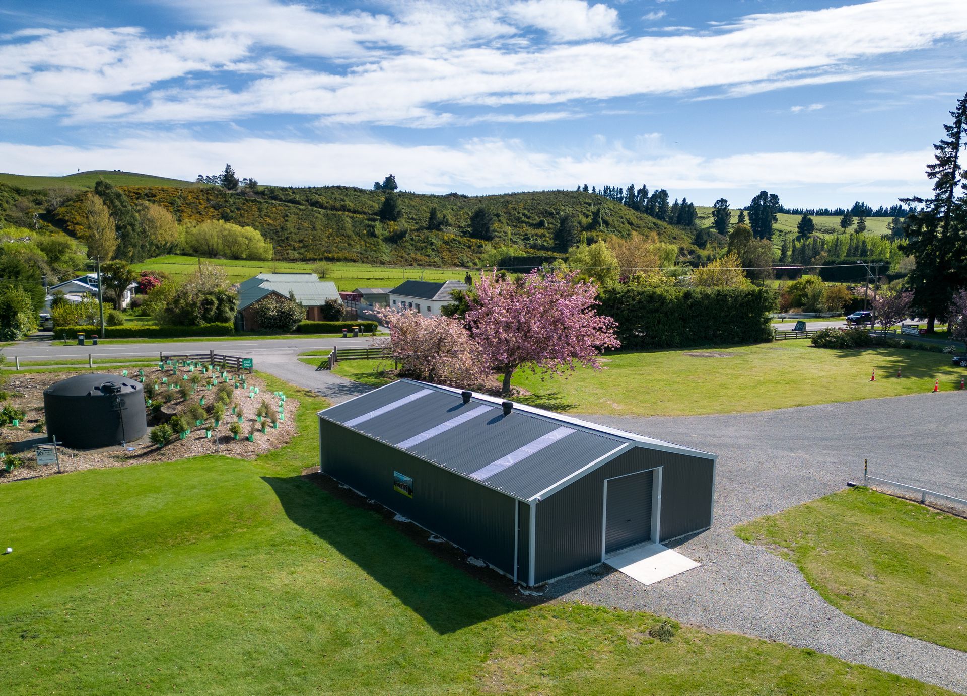An aerial view of a large shed in the middle of a lush green field.