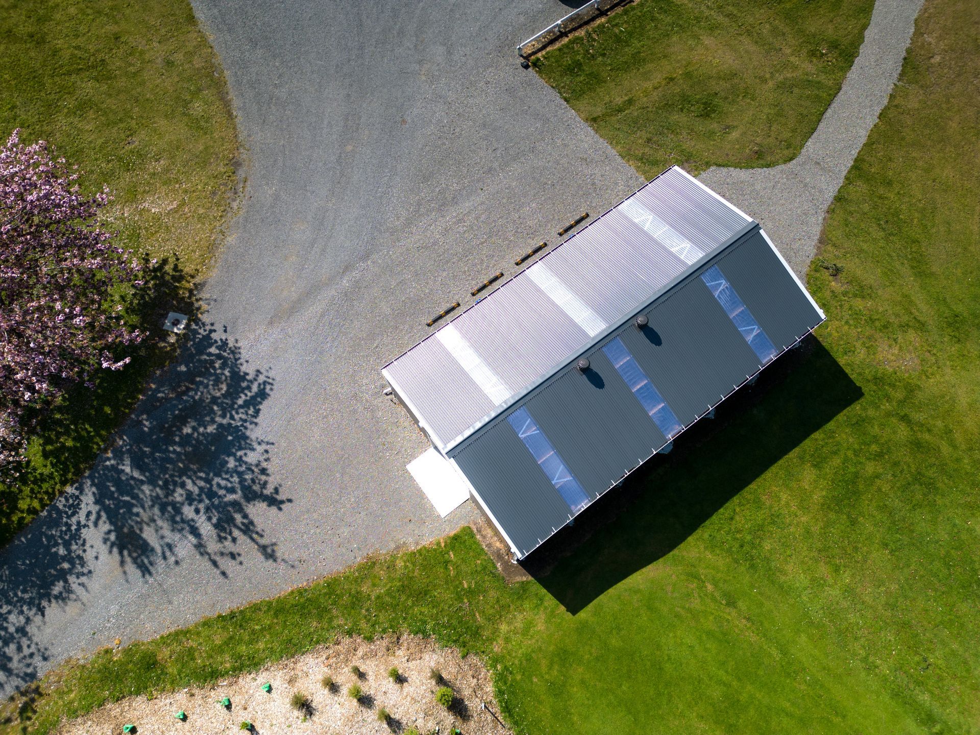 An aerial view of a house sitting on top of a lush green field.