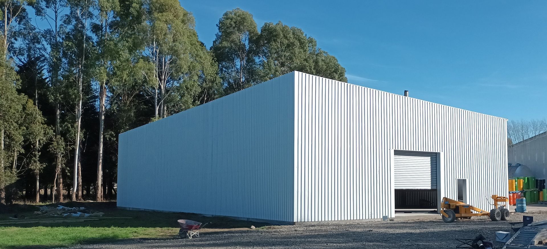 A large white building with a garage door and trees in the background.