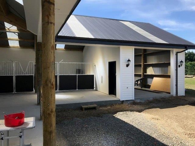 A white building with a gray roof and a black fence