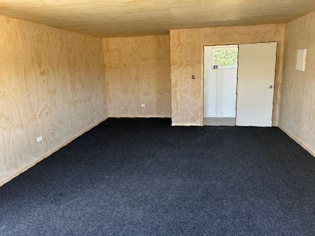 An empty room with a black carpet and a door.