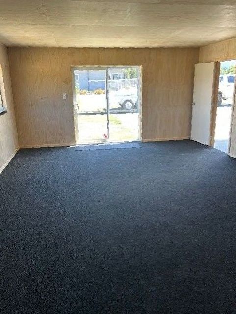An empty room with a sliding glass door and a black carpet.