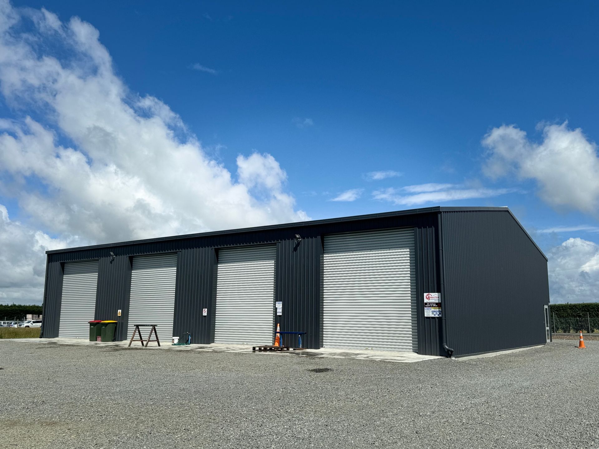 A large metal building with a blue sky and clouds in the background.