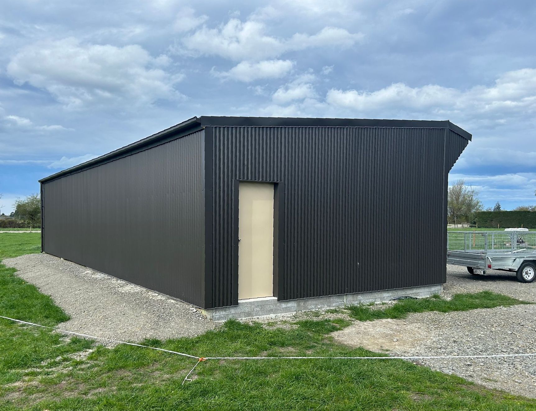 A black metal building with a door and a trailer parked in front of it.